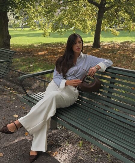 Woman in a blue and white striped shirt with ivory wide-leg trousers and brown suede buckle flats