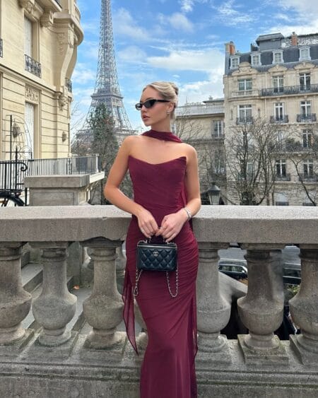 Woman in a wine red ruched one-shoulder maxi dress with a black bag, a burgundy fall outfit in Paris