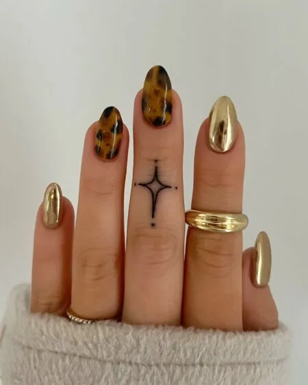 Almond-shaped tortoiseshell nails with amber and brown marbled details.