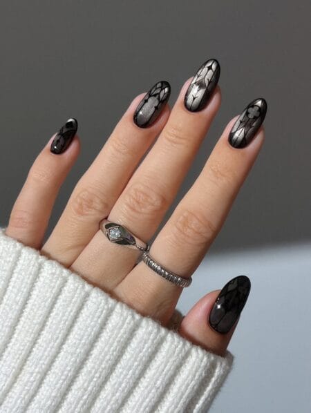 Black chrome almond nails with etched floral outlines