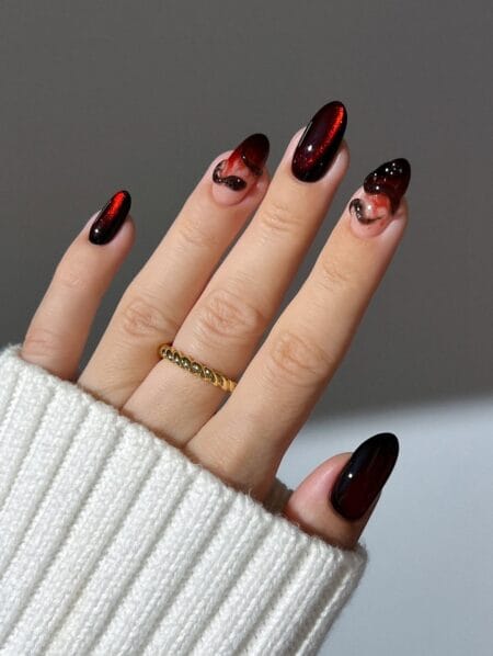 Blood red cat eye almond nails with dark swirl accents