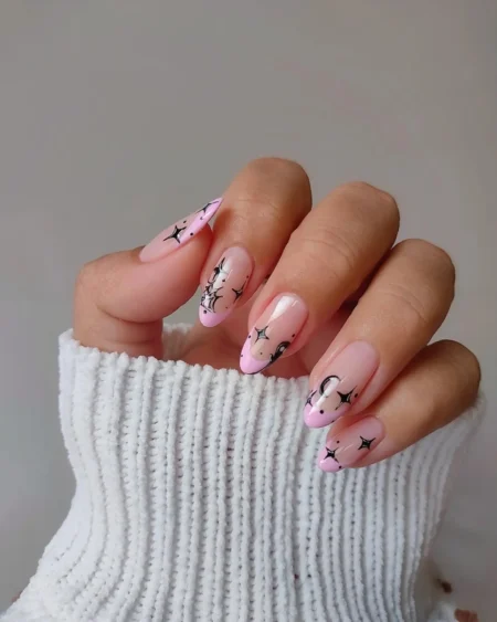 Soft pink almond nails with black stars and spider web accent