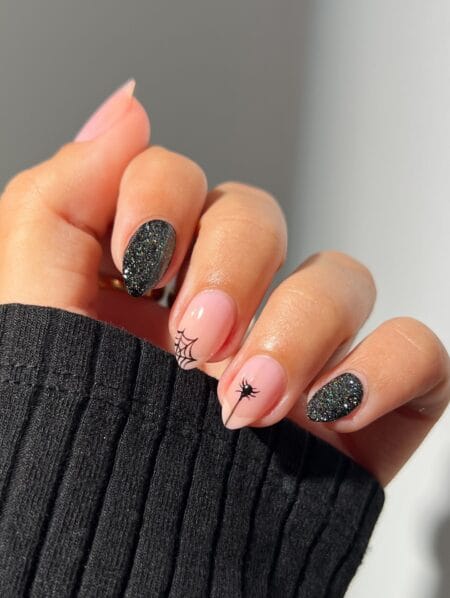 Soft pink nails with black glitter spider web and spider