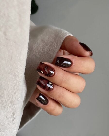 Almond-shaped tortoiseshell nails with amber and brown marbled details.