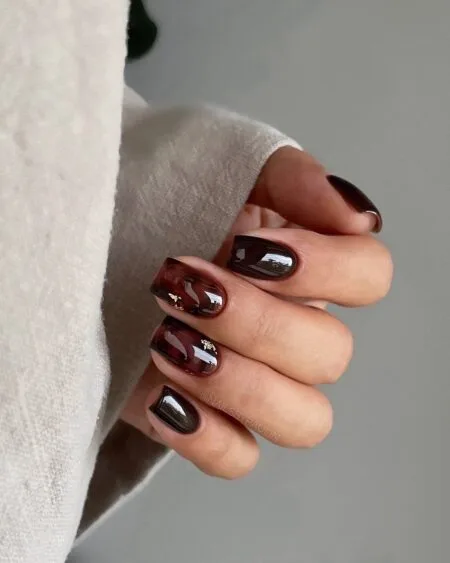 Almond-shaped tortoiseshell nails with amber and brown marbled details.