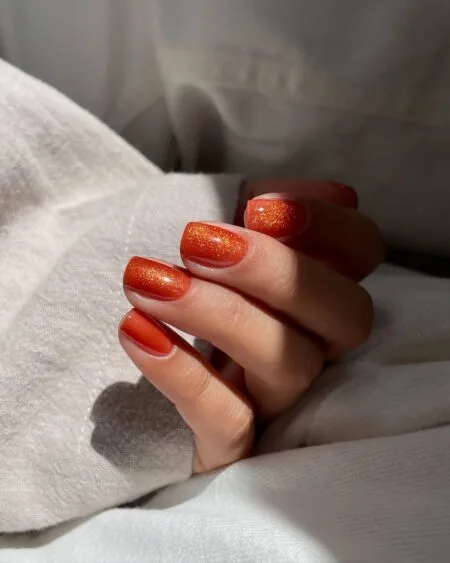 Burnt orange glossy nails in a warm pumpkin-inspired shade.