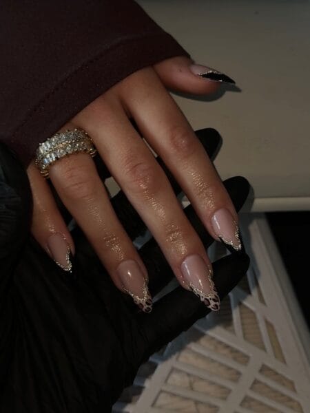Almond nails with black and leopard print tips outlined in gold glitter