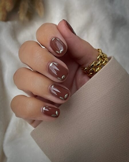 Short squoval nails in sheer terracotta with gold leaf detail
