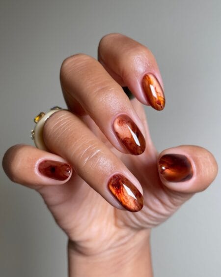 Smoky brown marble nails with elegant swirling details.