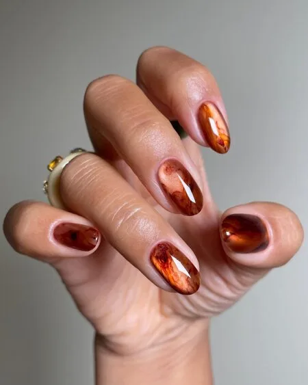 Smoky brown marble nails with elegant swirling details.