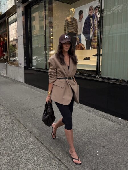 Belted camel blazer with black capri leggings, baseball cap and black thong sandals