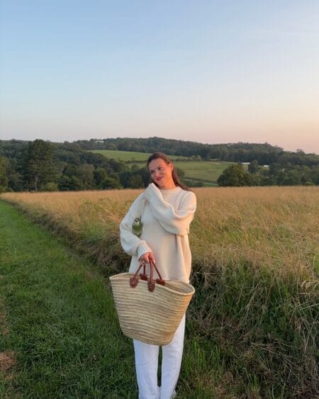 Oversized cream fisherman jumper with white wide-leg trousers and a straw basket bag