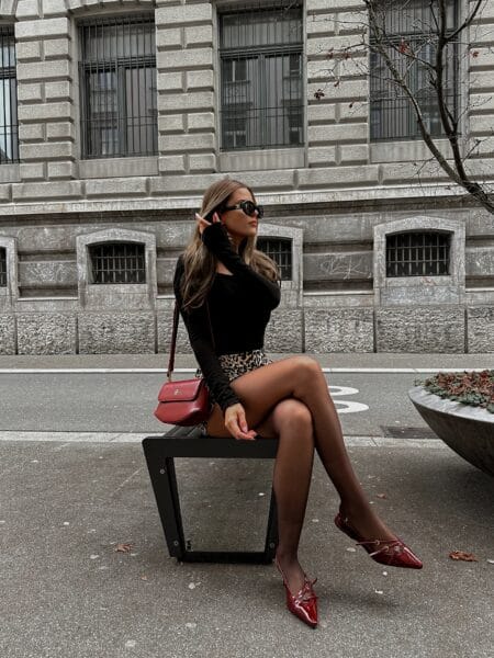 Black long-sleeve top with leopard-print mini skirt, sheer tights and burgundy patent slingbacks