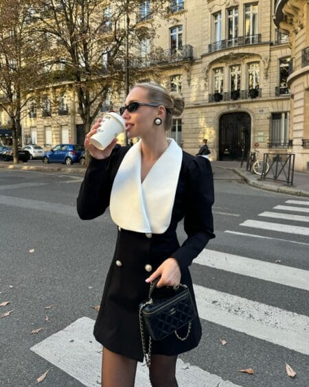 Black blazer dress with ivory shawl collar and pearl buttons worn with sheer tights on a Paris street