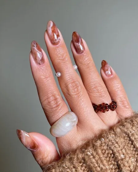 Smoky brown marble nails with elegant swirling details.