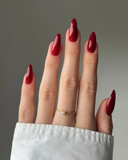 Dark cherry red nails with a glossy almond-shaped finish.