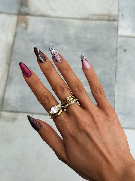 Long burgundy reptile print stiletto nails paired with tortoiseshell, zebra striping, and gold studs