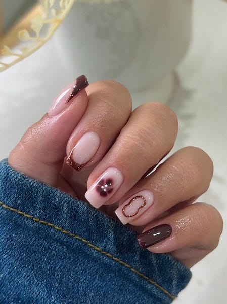 Dark chocolate square nails styled with a blooming petal accent and a textured bronze glitter border
