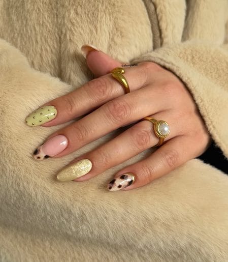 Soft yellow almond nails with gold studs paired with tortoiseshell tips and a metallic gold accent