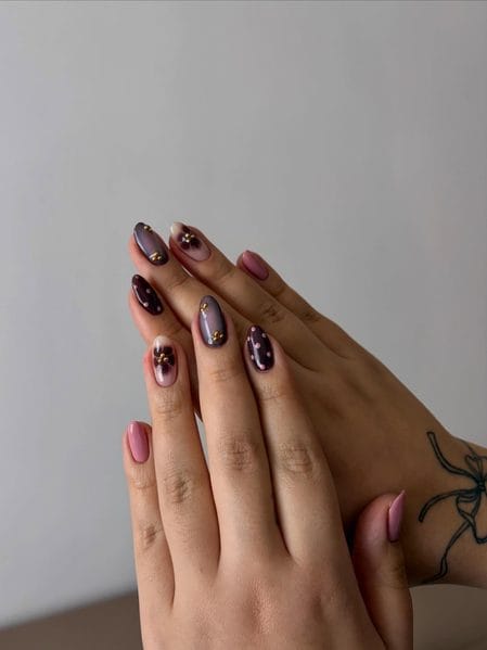 Smoky mauve and deep blackberry jelly nails with airbrushed floral centres and gold caviar beads
