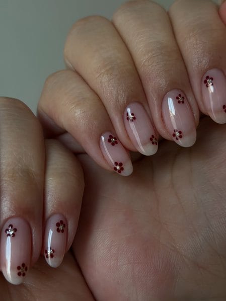 Glossy sheer natural nails dotted with miniature burgundy flower clusters