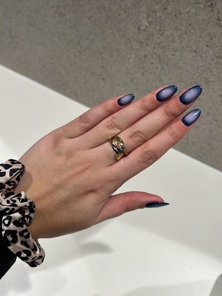 Long stiletto nails featuring a dark blue perimeter with a glowing lavender aura gradient