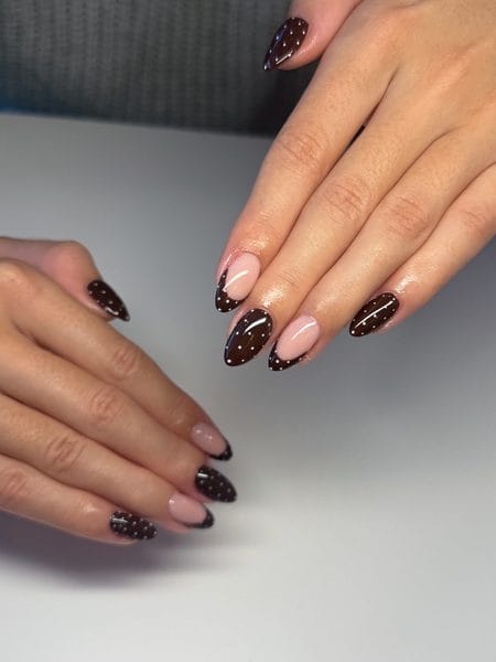 Polka dot chocolate almond nails with espresso polish, nude tips, and white dots