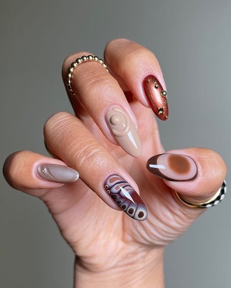 Sculpted earth-tone nails with taupe, espresso aura, copper cat-eye, and 3D details