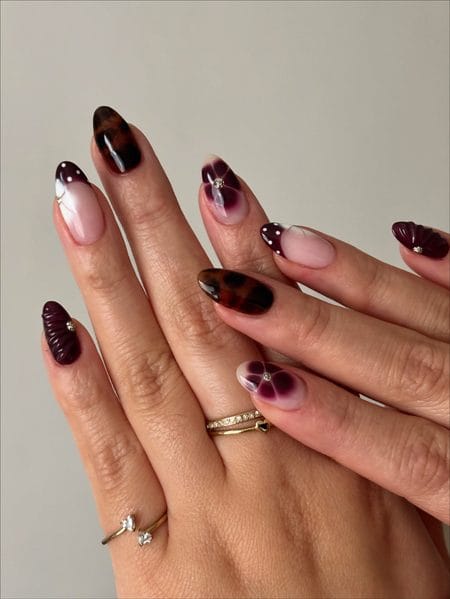 Burgundy-brown botanical nails with tortoiseshell, floral, gold, and 3D details