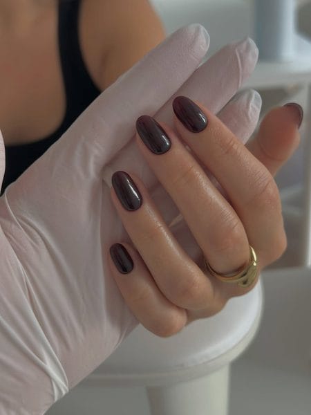 Dark chocolate oval nails with subtle plum undertones and a glossy finish