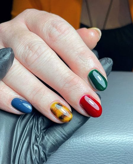 Emerald, crimson, and navy nails with a honey tortoiseshell accent