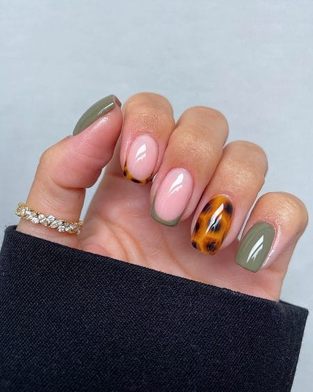 Sage green French tip nails with a golden honey tortoiseshell accent