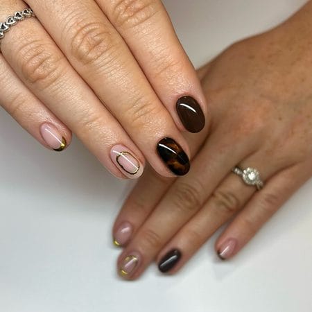 Short tortoiseshell French tip nails with nude polish and molten gold details