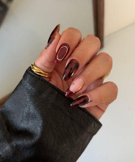 Deep burgundy almond nails with gilded tortoiseshell French tip accents