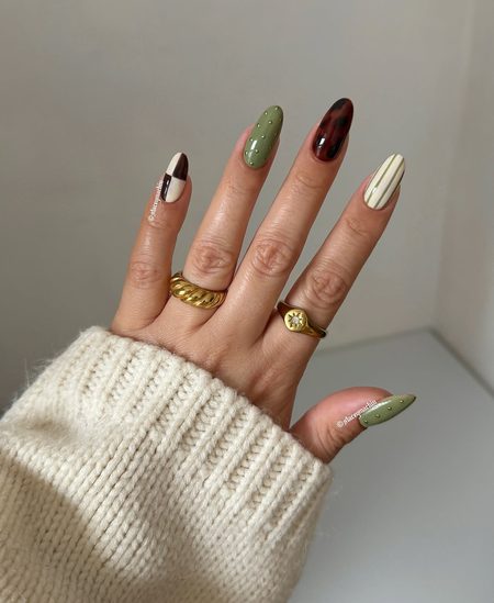 Sage green nails with gold studs, cream pinstripes, and tortoiseshell accent