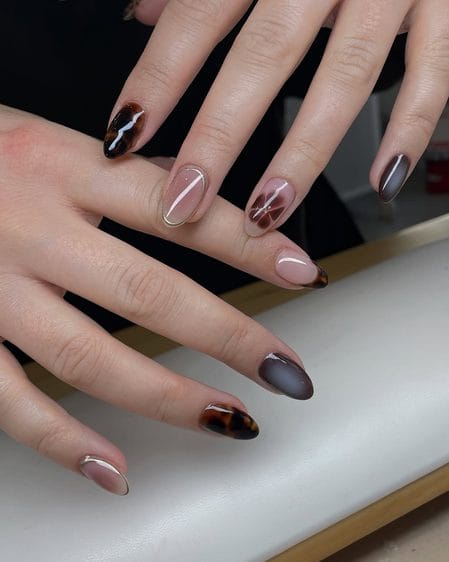 Sheer smoky grey nails with tortoiseshell floral and metallic accents