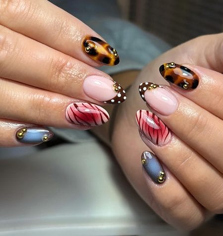 Mixed animal print nails with brown polka dots, tortoiseshell, and gold studs