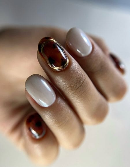 Oyster chrome nails with a 3D tortoiseshell accent framed in gold